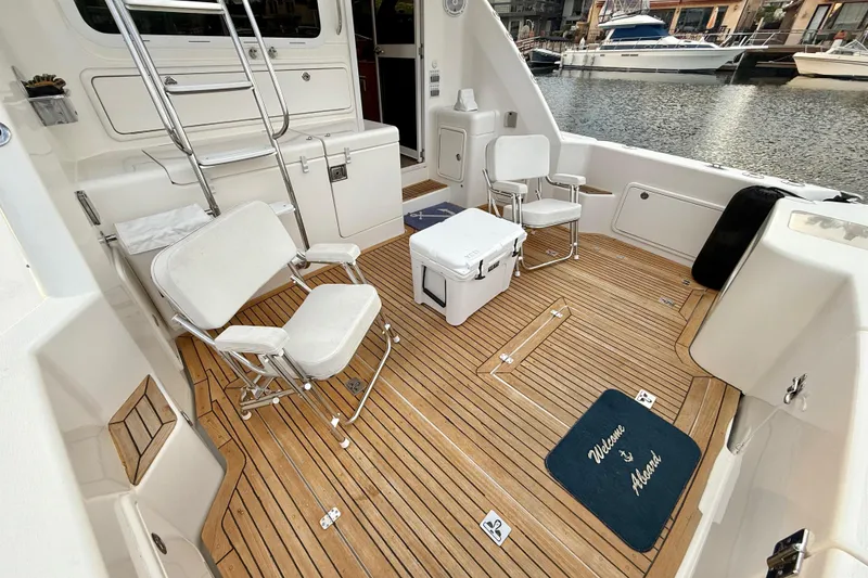 Slide: The Image of Riviera 40 Flybridge 2001 yacht deck with chairs and cooler, docked by the water. - 35