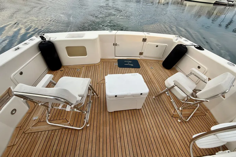 Slide: The Image of Riviera 40 Flybridge 2001 boat deck with chairs and cooler on wooden flooring. - 37