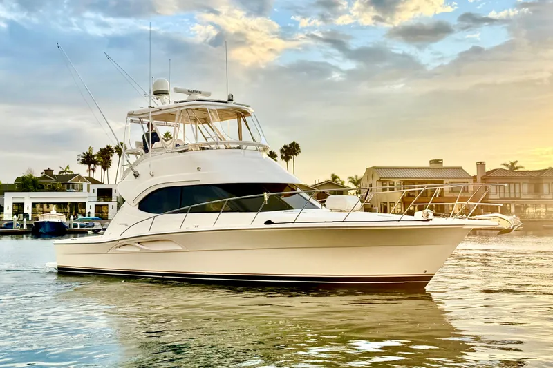 Slide: The Image of 2001 Riviera 40 Flybridge yacht cruising at sunset near waterfront homes. - 4