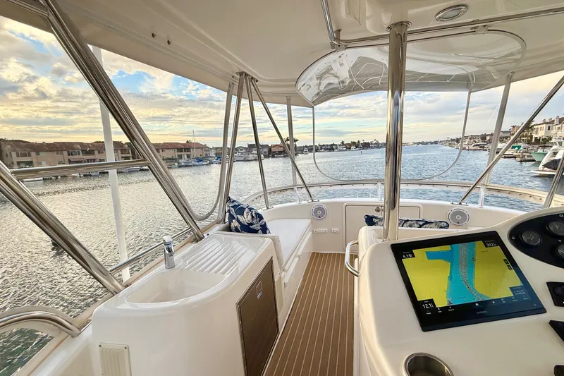 Slide: The Image of Flybridge view of 2001 Riviera 40, featuring navigation screen and waterfront scenery. - 44