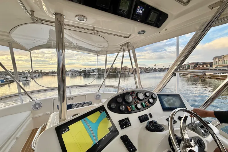 Slide: The Image of 2001 Riviera 40 Flybridge yacht cockpit with navigation equipment, overlooking serene waterfront homes. - 45