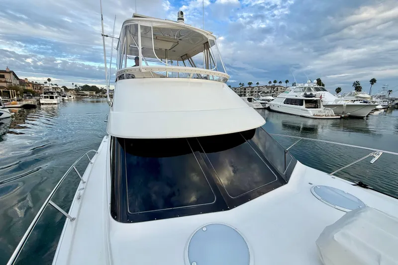 Slide: The Image of 2001 Riviera 40 Flybridge yacht docked in a marina under a cloudy sky. - 54