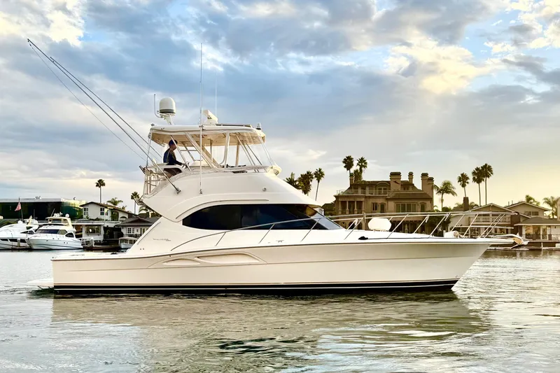 Slide: The Image of 2001 Riviera 40 Flybridge yacht cruising near waterfront homes under a cloudy sky. - 6
