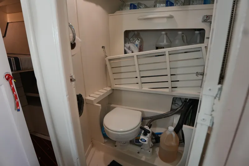 Slide: The Image of 1983 Hunter 34 sailboat bathroom with storage shelves and marine toilet. - 17