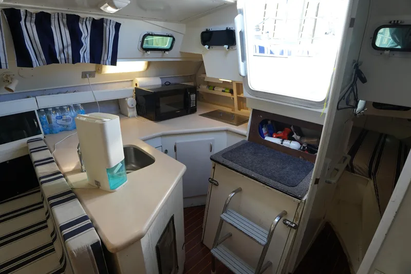 Slide: The Image of Interior of 1983 Hunter 34 sailboat galley with striped curtains and compact kitchen setup. - 22