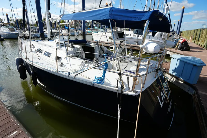 Slide: The Image of 1983 Hunter 34 sailboat docked in marina, featuring blue canopy and sleek design. - 5