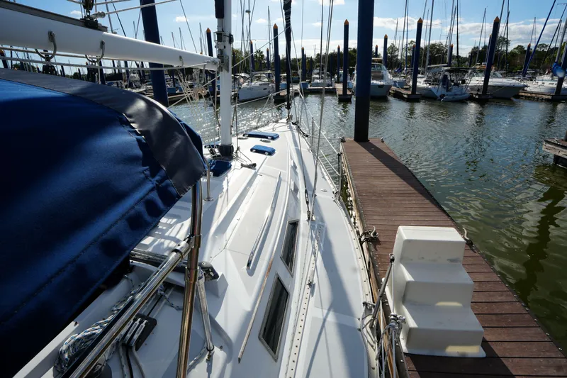 Slide: The Image of 1983 Hunter 34 sailboat docked at marina, sunny day, blue canopy, calm waters. - 8