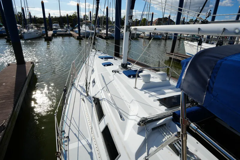 Slide: The Image of 1983 Hunter 34 sailboat docked in a sunny marina, showcasing sleek design and rigging. - 9