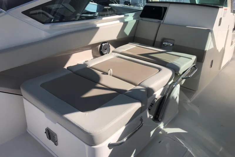 Slide: The Image of 2024 Boston Whaler 280 Vantage interior seating with beige cushions and stainless steel handles. - 7