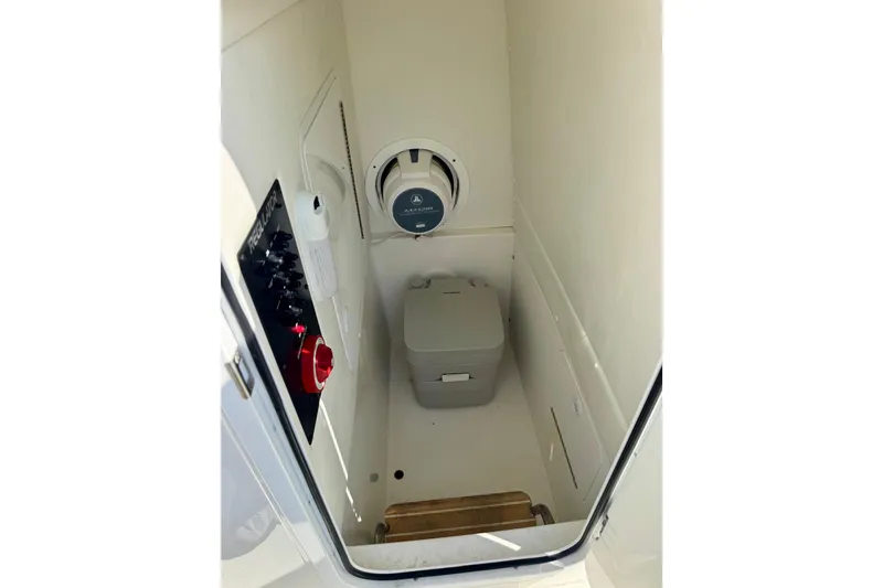 Slide: The Image of 2021 Regulator 26XO boat interior with compact toilet and control panel. - 14
