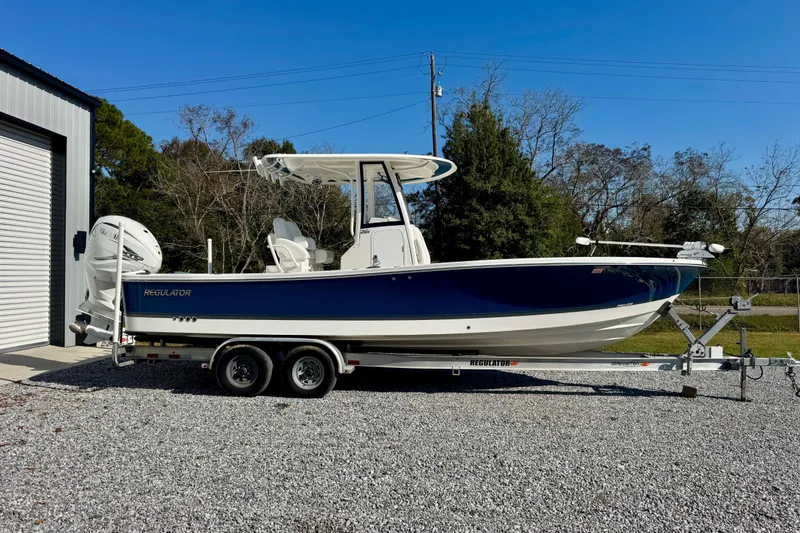 Slide: The Image of 2021 Regulator 26XO boat on trailer, parked outdoors near a building. - 2