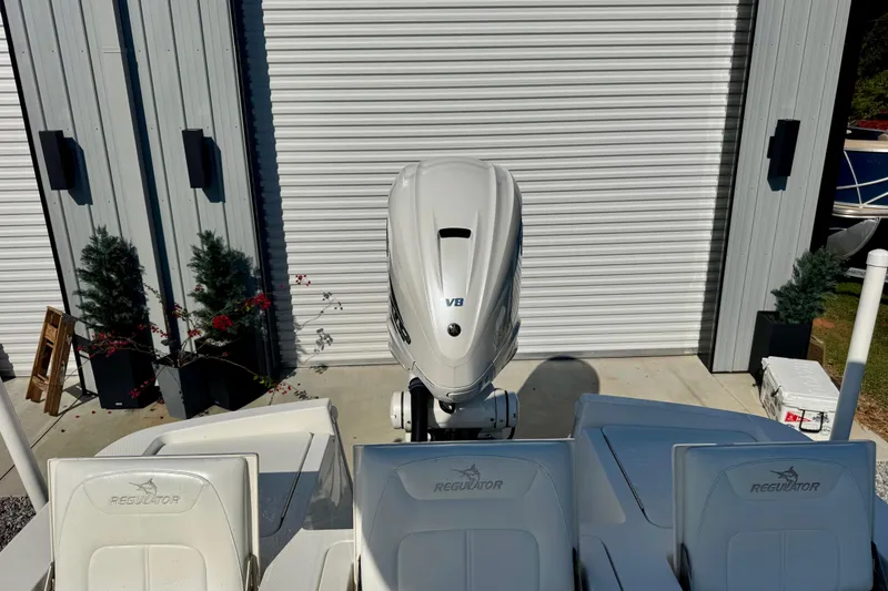 Slide: The Image of 2021 Regulator 26XO boat with V8 engine, parked near a metal building. - 7