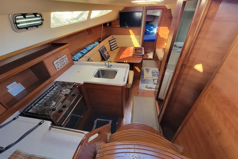 Slide: The Image of Interior of 2013 Hunter 33 sailboat with kitchen, dining area, and wooden finish. - 3