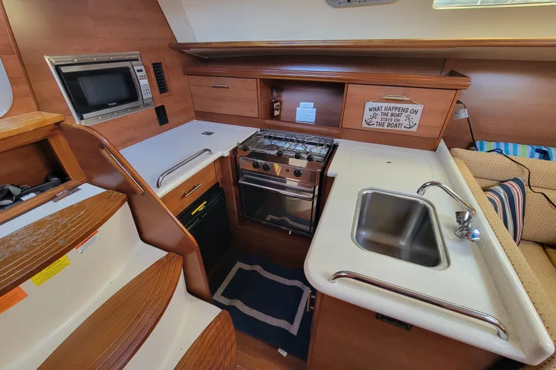 Slide: The Image of Compact kitchen in a 2013 Hunter 33 sailboat with stove, sink, and microwave. - 4