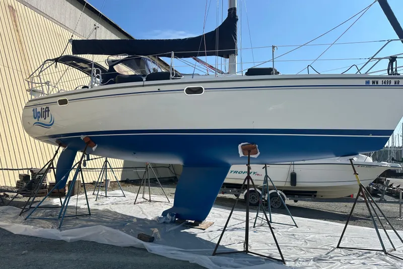 Slide: The Image of 2005 Catalina 320 Sloop sailboat on stands, named "Uplift," in a boatyard. - 6