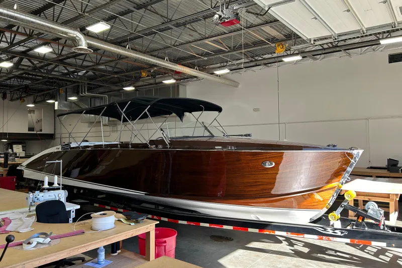 Slide: The Image of 2013 StanCraft 34 Highboy Deluxe boat in a workshop, showcasing sleek wooden design. - 8