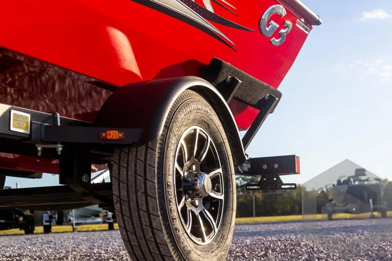 Slide: The Image of 2026 G3 Sportsman 1710 SE boat trailer, red exterior, close-up of wheel and fender. - 17