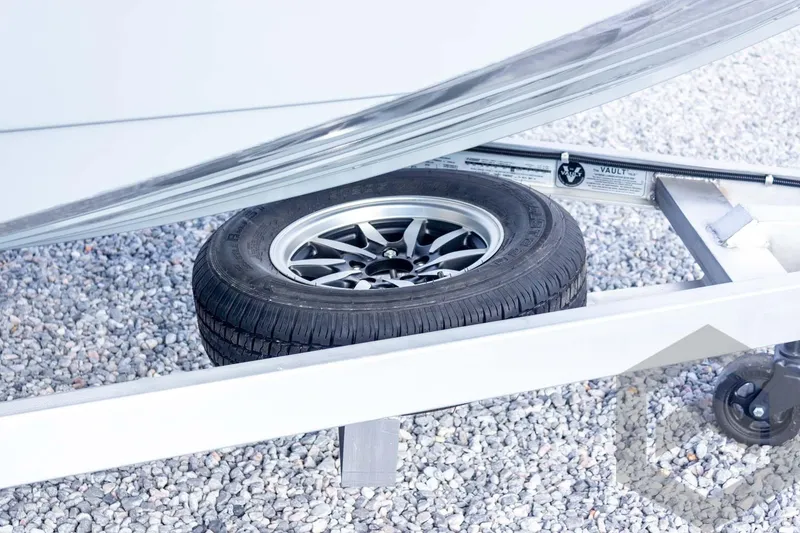 Slide: The Image of Spare tire under G3 Bay 19 GX trailer, 2026 model, on gravel surface. - 19