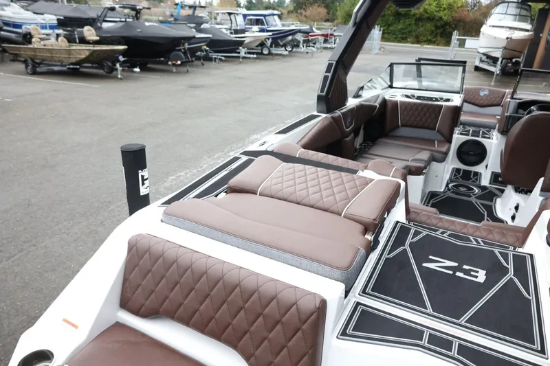 Slide: The Image of 2026 Tigé Z3 boat interior with brown quilted seats and sleek design in a marina. - 11