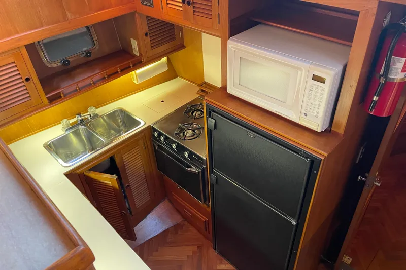 Slide: The Image of 1985 Nova 40 Sundeck Aft Cabin kitchen with stove, microwave, and double sink. - 13