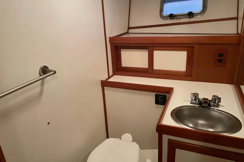 Slide: The Image of 1985 Nova 40 Sundeck Aft Cabin bathroom with sink, toilet, and porthole window. - 19