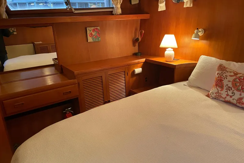 Slide: The Image of Cozy 1985 Nova 40 Sundeck Aft Cabin interior with bed, lamp, and wooden furnishings. - 21