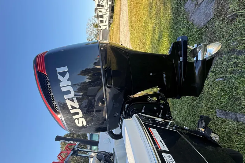 Slide: The Image of Suzuki outboard motor on 2021 Carolina Skiff 26 Ultra Elite boat, parked on grass. - 15