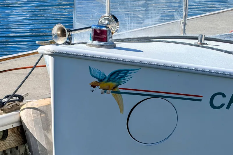 Slide: The Image of 1989 Duffy 20 boat with colorful parrot design on the side, docked by the water. - 2