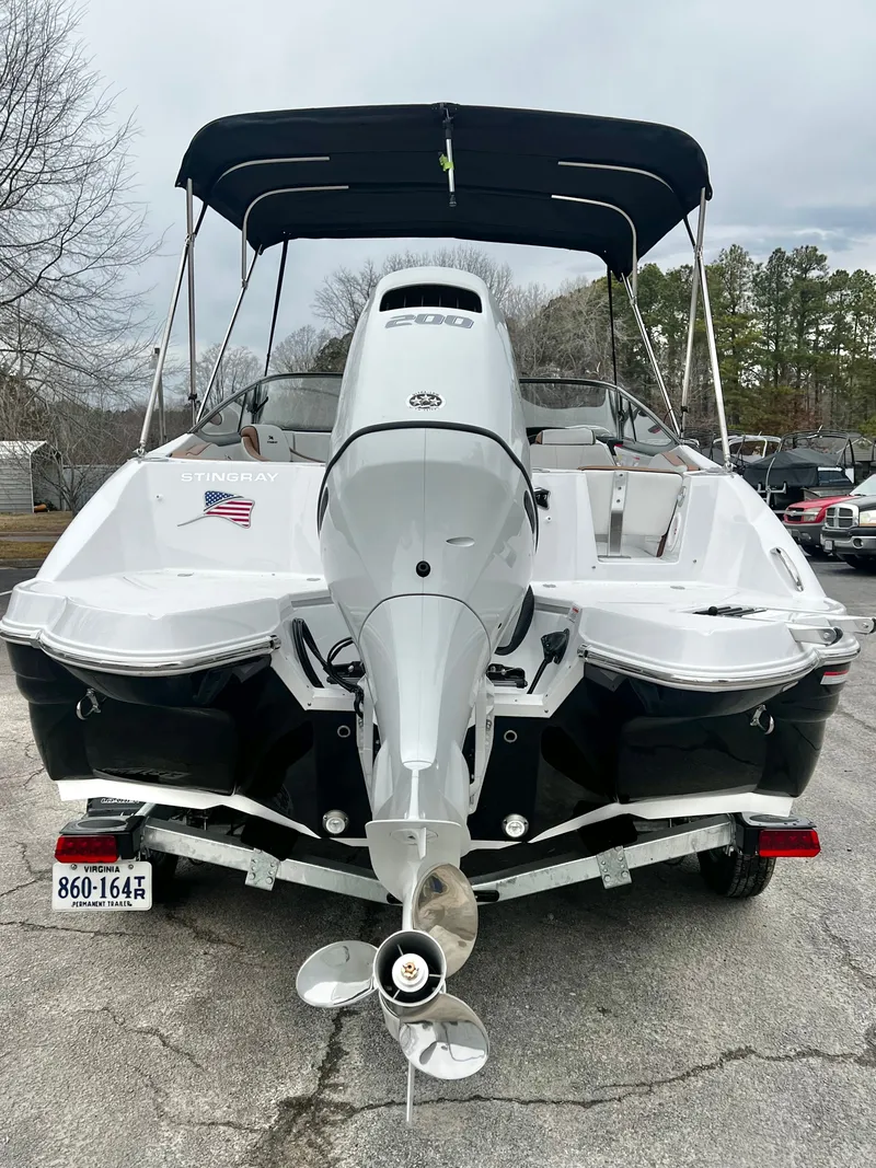 Slide: The Image of 2026 Stingray 211DC boat with outboard motor, parked on a lot. - 4