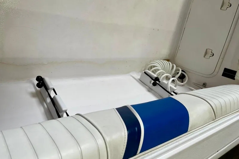 Slide: The Image of 2001 Pro-Line 25 Sport CC boat interior with white and blue seating and coiled hose. - 20
