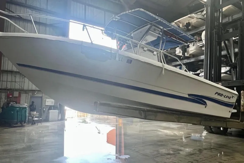 Slide: The Image of 2001 Pro-Line 25 Sport CC boat in a warehouse, elevated on a forklift. - 3