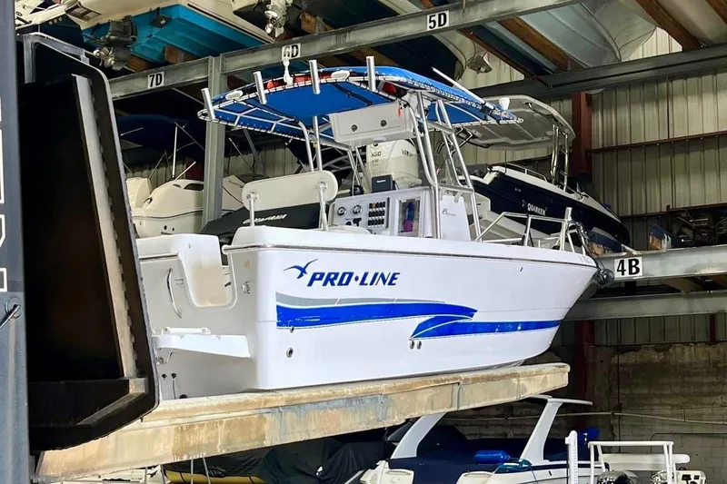 Slide: The Image of 2001 Pro-Line 25 Sport CC boat in storage, featuring blue accents and a sturdy design. - 4