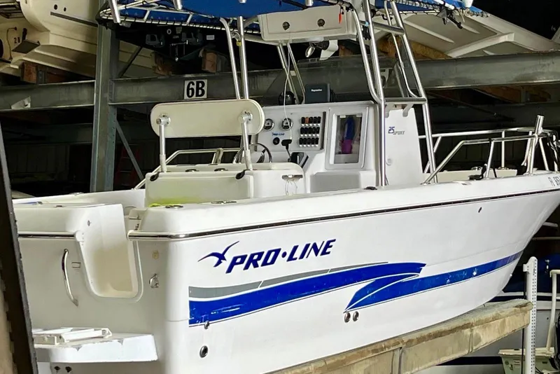 Slide: The Image of 2001 Pro-Line 25 Sport CC boat in storage, featuring sleek design and blue accents. - 5
