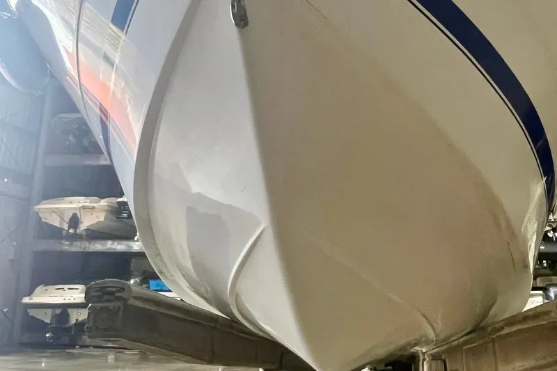 Slide: The Image of 2001 Pro-Line 25 Sport CC boat hull in storage, showcasing sleek design and blue stripe. - 6