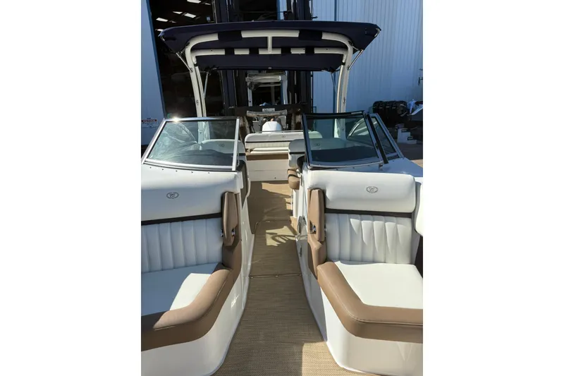 Slide: The Image of 2020 Cobalt 25SC boat interior with white and tan seating, docked in a marina. - 12