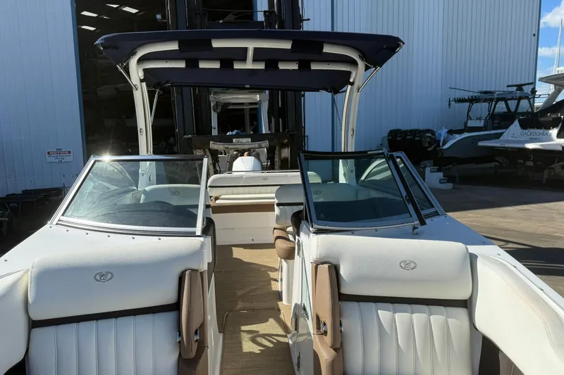 Slide: The Image of 2020 Cobalt 25SC boat interior with white seating and windshield, docked near a warehouse. - 13