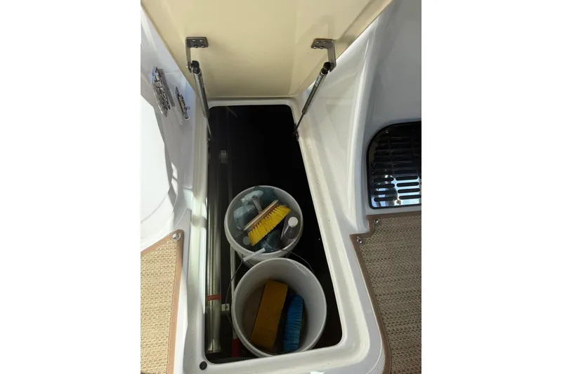 Slide: The Image of Open storage compartment on 2020 Cobalt 25SC boat with cleaning supplies. - 22