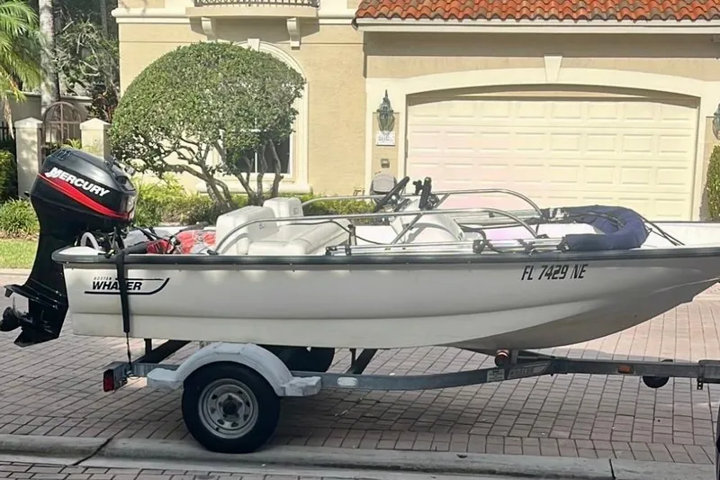 The Image of 2006 Boston Whaler 130 Sport boat on trailer, parked in front of a house. - 0