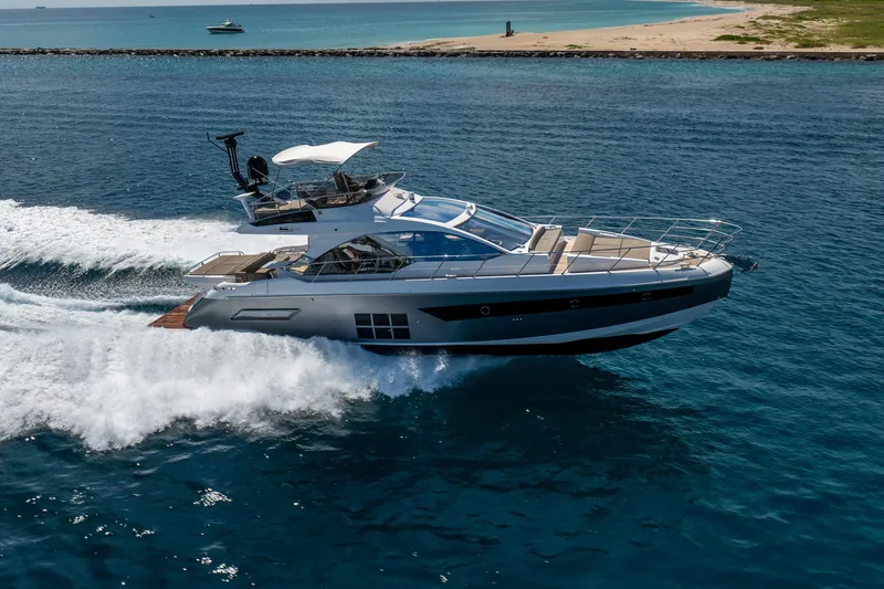 Slide: The Image of Azimut S6 Sportfly 2021 yacht cruising on open water near a sandy coastline. - 12