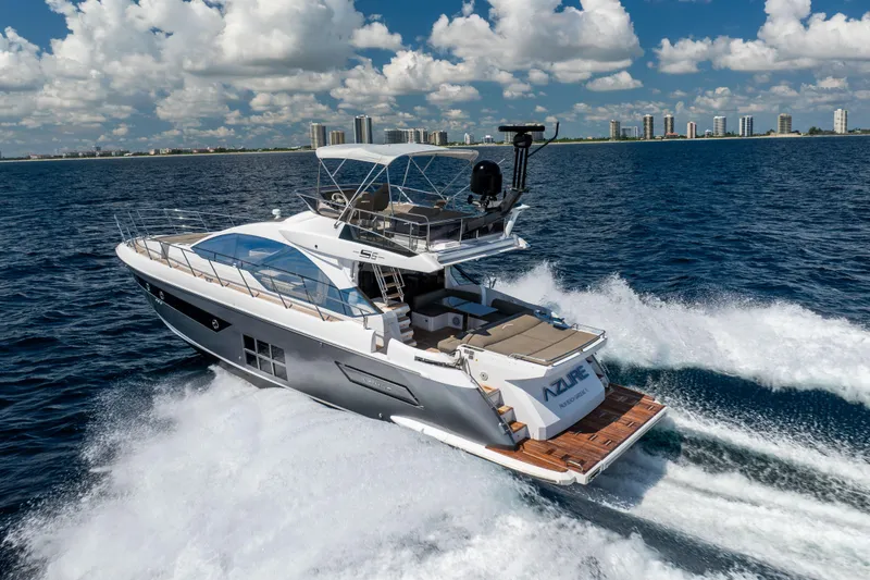 Slide: The Image of 2021 Azimut S6 Sportfly yacht cruising on open water with city skyline backdrop. - 3