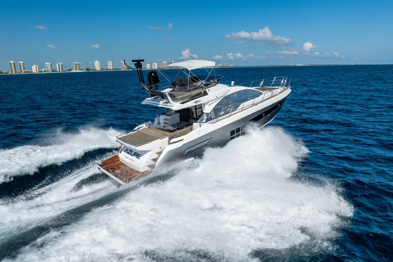 Slide: The Image of 2021 Azimut S6 Sportfly yacht cruising on open water with city skyline backdrop. - 56