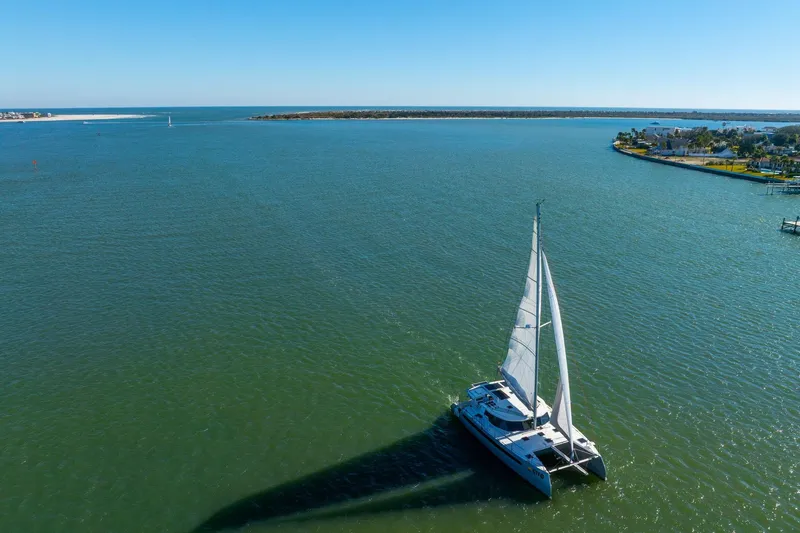 Slide: The Image of Sailing catamaran Balance 482, 2024 model, gliding on serene blue waters under clear skies. - 128