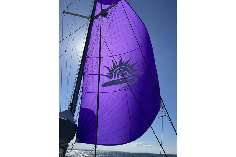 Slide: The Image of Purple sail with sun design on Balance 482 yacht, 2023 model, against clear blue sky. - 134
