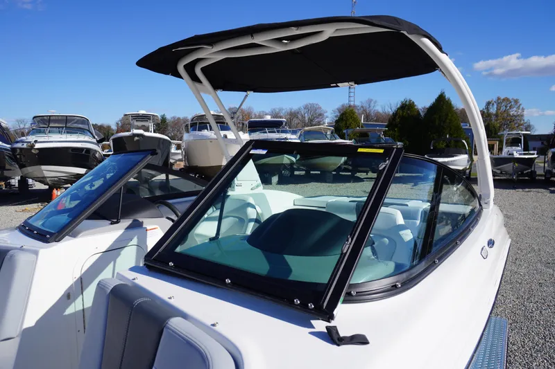 Slide: The Image of 2026 Chaparral 23 SSi boat with sleek design and black canopy, displayed outdoors. - 66