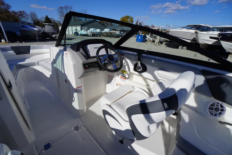 Slide: The Image of 2026 Chaparral 23 SSi boat interior with steering wheel and seating, docked outdoors. - 17