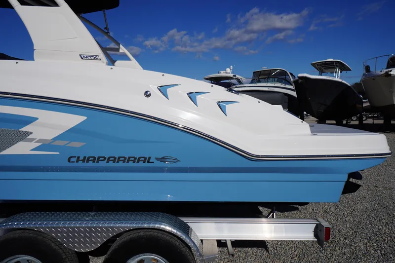 Slide: The Image of 2026 Chaparral 23 SSi boat in blue and white on a trailer under a clear sky. - 2