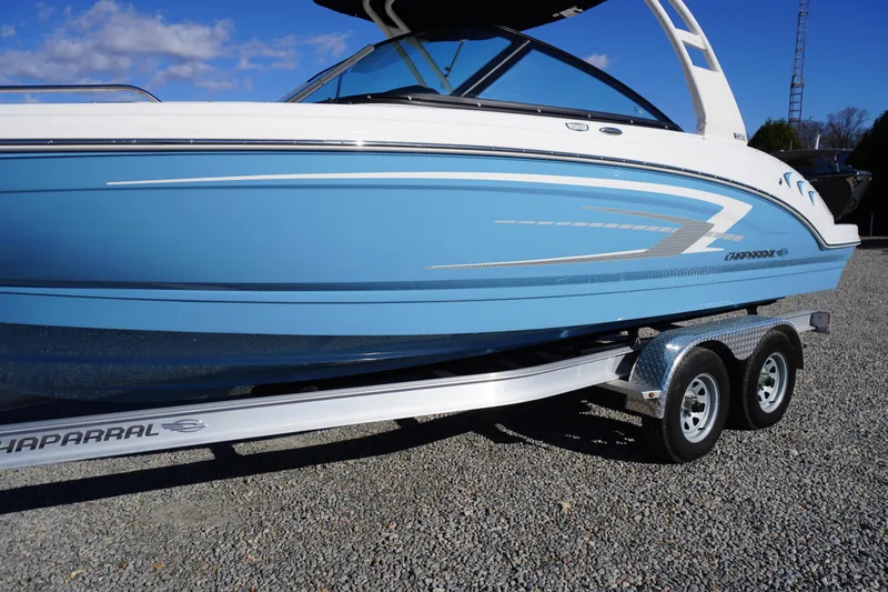 Slide: The Image of 2026 Chaparral 23 SSi boat on trailer, blue and white design, parked on gravel. - 69