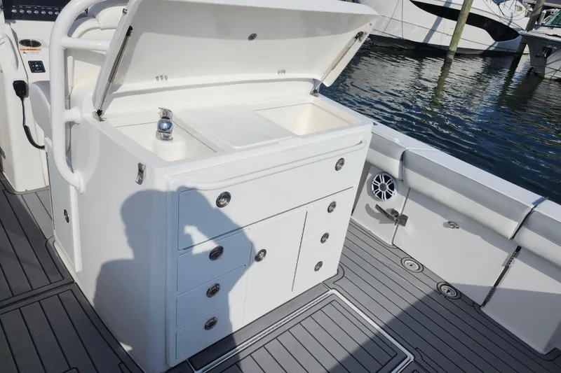 Slide: The Image of 2022 Regulator 34 boat interior with open storage compartment and sink by the water. - 25