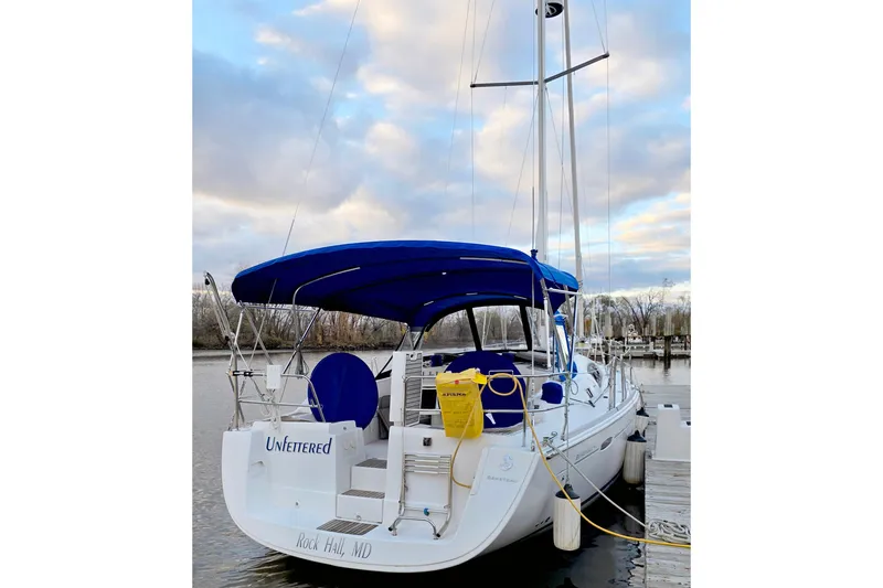 Slide: The Image of 2011 Beneteau 40 sailboat docked, featuring blue canopy and serene waterfront setting. - 4