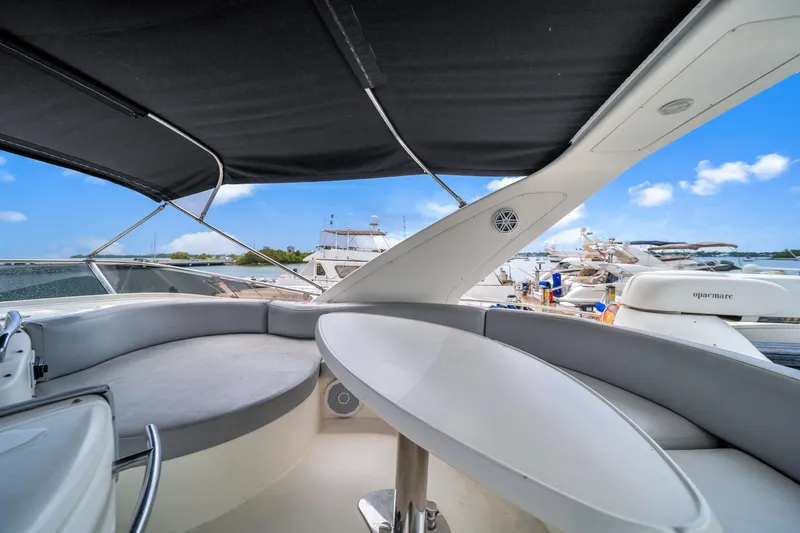 Slide: The Image of 2006 Azimut FLY 55 yacht interior with seating and table, docked under blue sky. - 11